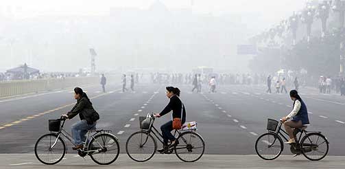  SMOG: Kinesiske kvinner sykler gjennom tett smog i forurensede Beijing, en av de tretten byene som har en brun sky hengende over seg.